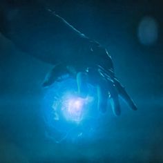 two hands reaching towards a glowing object in the dark