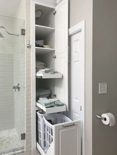 a white bathroom with an open shower door and shelves filled with towels, toiletries and other items