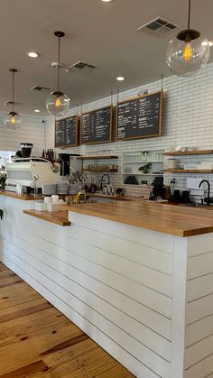 the inside of a coffee shop with wood floors and white brick walls, along with hanging lights