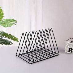 an alarm clock sitting on top of a white table next to a wire holder with triangles