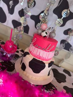 a pink and black cake sitting on top of a table next to a cow print wall