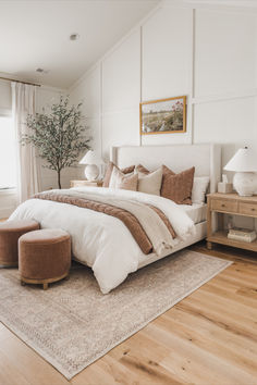 a large white bed sitting in a bedroom on top of a hard wood floor next to a window