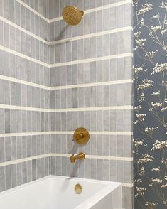 a white bath tub sitting under a faucet next to a wall mounted shower head