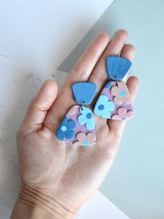 a person is holding some colorful earrings in their hand and it looks like they have flowers on them