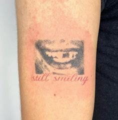 a person with a tattoo on their arm that says still smiling and an image of a mouth