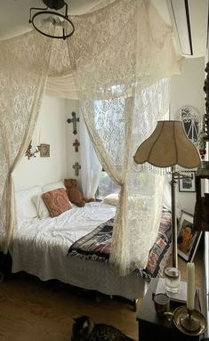 a white bed sitting under a window next to a lamp on top of a wooden floor