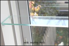 a glass shelf sitting in front of a window with the words write warning needles on it