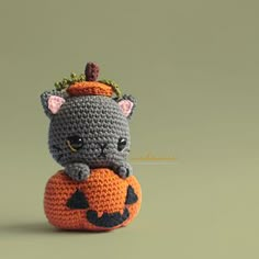 a small crocheted cat sitting on top of a pumpkin with a crown on its head