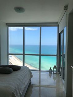 a bedroom with a large window overlooking the beach and ocean is pictured in this image