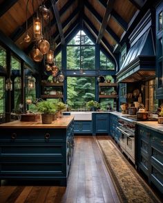 a large kitchen with blue cabinets and wooden floors is lit by pendant lights hanging from the ceiling