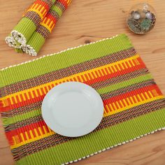 a place mat with a white plate on top of it next to some napkins