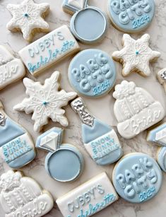 cookies decorated with blue and white frosting are arranged on a marble countertop for a baby's first christmas or new year celebration