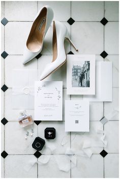 wedding stationery and shoes on the floor in front of a tiled wall with black and white tiles