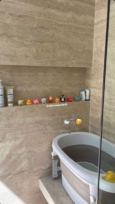 a bath tub sitting next to a wall with shelves on the side and rubber ducks in it