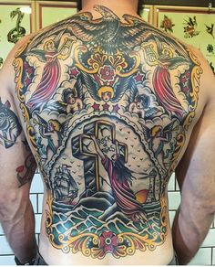 the back of a man with tattoos on his body and cross in front of him