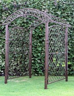 an iron garden trellis in front of a green wall