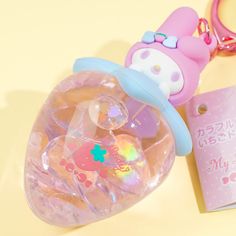 a hello kitty keychain is sitting on a table next to a pink bag