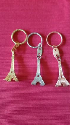 three metal key chains with the eiffel tower on them