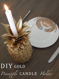 a pineapple candle holder sitting on top of a wooden table next to a plate