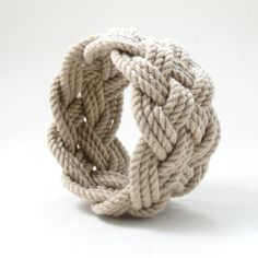 a white rope bracelet is shown against a white background and looks like it's made out of yarn