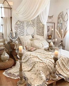 a bedroom with white bedding and candles on the nightstands in front of it