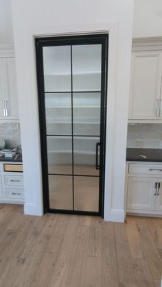 an empty kitchen with white cabinets and black glass doors