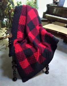 a red and black plaid blanket sitting on top of a chair next to a piano