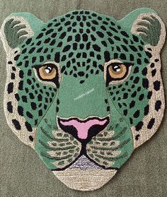 a close up of a green and black leopard's face on a gray surface