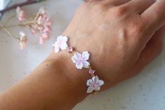 a woman's hand with flowers on it and a bracelet in the foreground