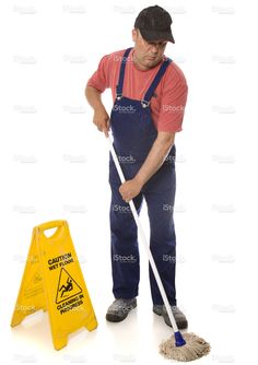 a man sweeping the floor with a mop and broom in front of a caution sign