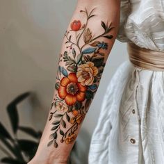 a woman's arm with flowers and leaves tattooed on the left side of her arm