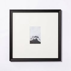 a black and white photo hanging on the wall next to a framed photograph with mountains in the background