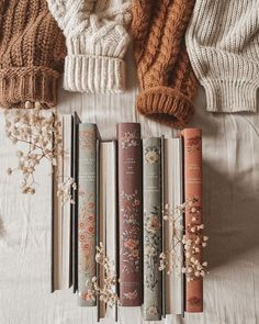 four books lined up next to each other on top of a white bed covered in blankets