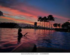 a woman is swimming in the pool at sunset