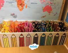 there are many different colored pencils in the box on the desk next to the map