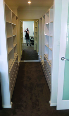 a woman taking a photo in the mirror of a walk - in closet with shelving