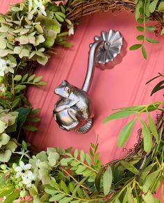 a close up of a metal door handle on a pink door with green leaves and flowers