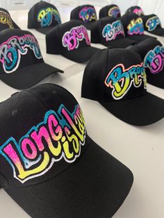 "one-of-a-kind custom-made black baseball hats! Choose one(1) Word and from up to (4) colors.  personalize with your name, town, city or brand.  since personalization is on a hat we have limited space for writing.  please personalize with one (1). Each hat is meticulously hand-painted, creating a truly unique and eye-catching effect.  With whimsical, curvy letters that add a touch of playfulness, every design is a work of art. What sets our hats apart is the dazzling embellishment of glitter, adding a touch of sparkle and personality. No two hats are exactly the same, making each piece a special and individual expression of style. Stand out from the crowd and showcase your own distinct flair with our hand-painted hats that are as unique as you are! please note: all hats will be made with g Black Baseball Hat, Painted Hats, Merch Ideas, Party Inspo, Store Front, Trucker Cap, Your Name, Caps Hats, Accessories Hats