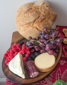 an assortment of cheeses, bread and berries on a plate