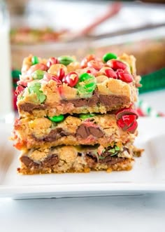 three pieces of christmas cookie bars stacked on top of each other with candy in the middle