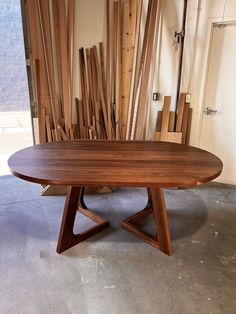 a wooden table sitting on top of a floor next to a pile of wood planks