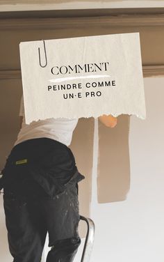 a person on a ladder painting the wall with a sign over their head that says comment