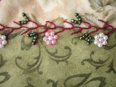 beaded flowers on fabric with pink and white beads hanging from the back of it