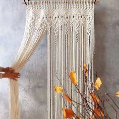 a white macrame hanging on a wall next to a vase with yellow flowers