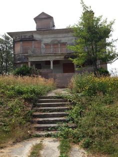 an old abandoned house with steps leading up to it