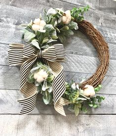 a wreath with white flowers and greenery on a wooden background, hanging on a wall