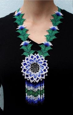 a woman wearing a black top with a green and blue beaded necklace on her neck