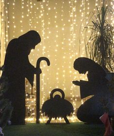 the silhouettes of two people and a baby are in front of a christmas tree