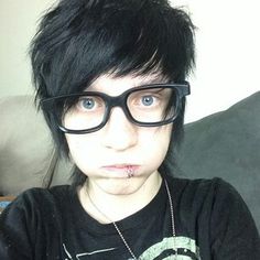 a person with black hair and glasses making a funny face while sitting on a couch