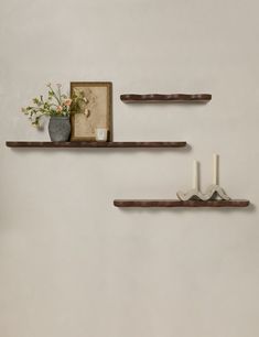 two wooden shelves with candles and flowers on them